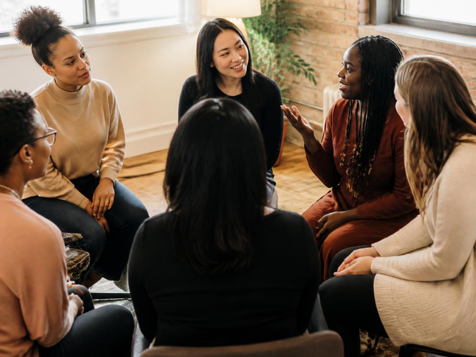 A diverse circle of women talking and laughing together in a community space